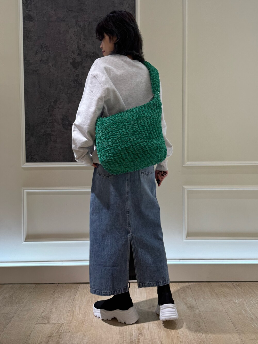 グレー系のスウェット、ブルー系のデニムスカート、ホワイト系のブーツを着用したレディースの冬コーディネートの2枚目の写真