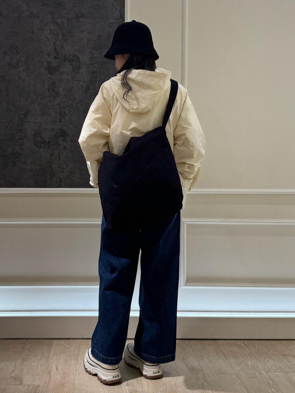 ブルー系のデニムパンツ、ホワイト系のスニーカー、ブラック系のショルダーバッグを着用したレディースの春コーディネートの3枚目の写真