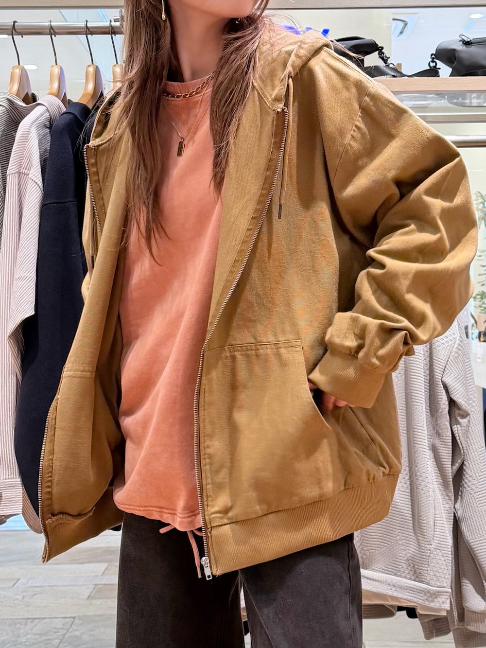 ベージュ系のブルゾン、オレンジ系のスウェット、ブルー系のデニムパンツを着用したレディースの春コーディネートの2枚目の写真