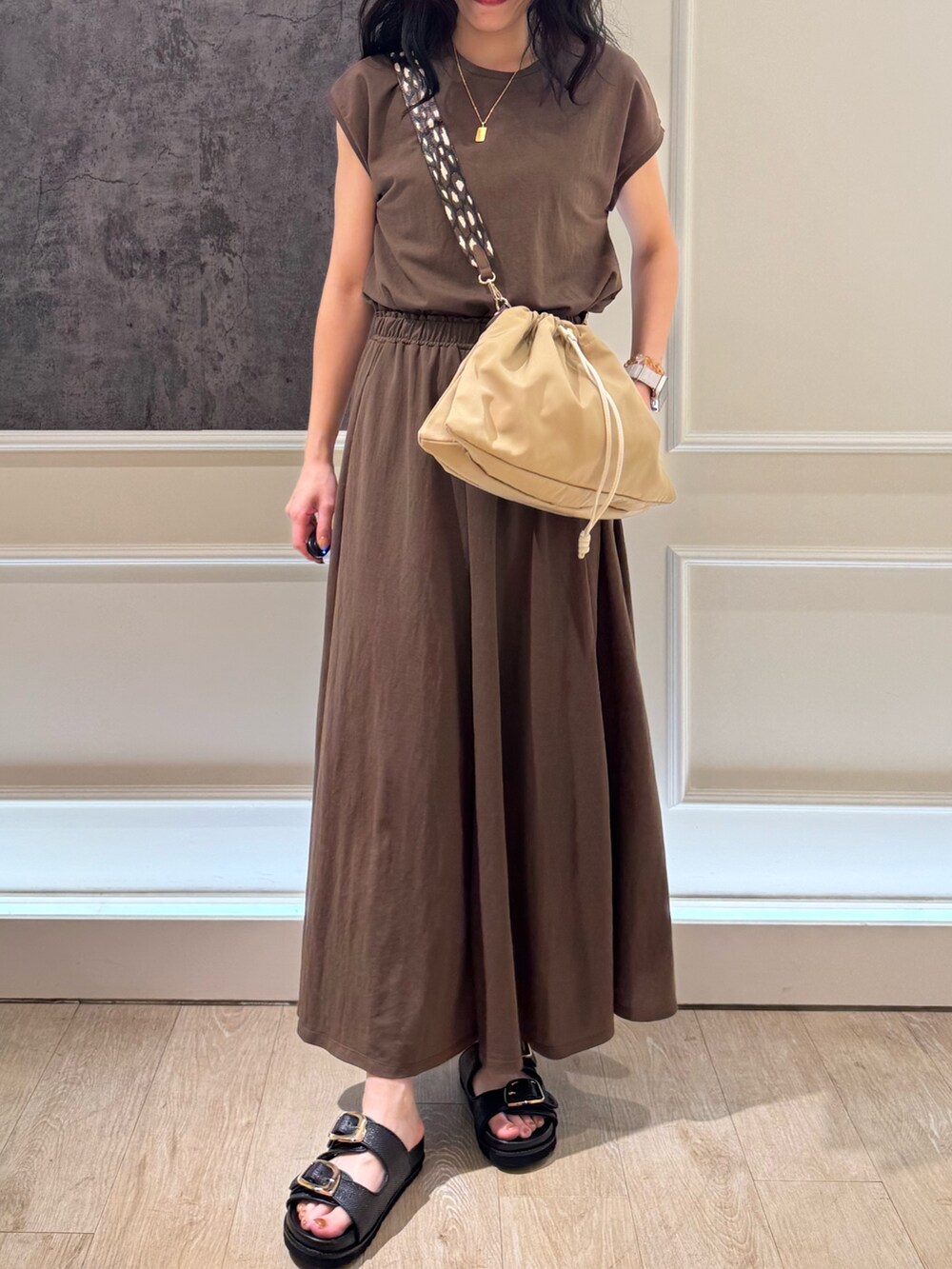 ブラウン系のTシャツ/カットソー、ブラウン系のスカート、ベージュ系のショルダーバッグを着用したレディースの夏コーディネートの3枚目の写真