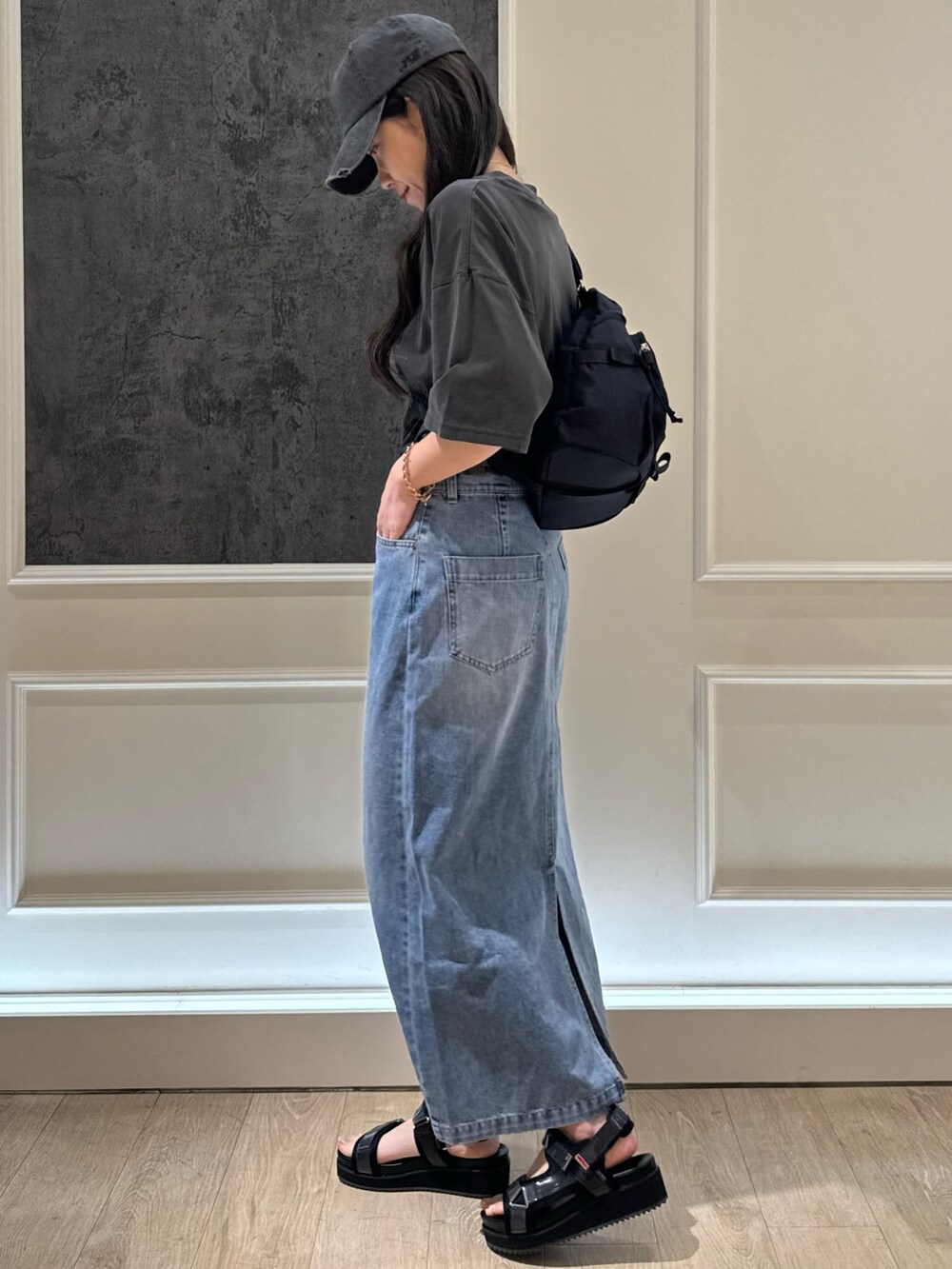 ブラック系のTシャツ/カットソー、ブルー系のデニムスカート、ブラック系のショルダーバッグを着用したレディースの春コーディネートの3枚目の写真