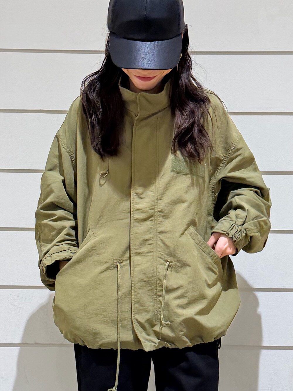 グリーン系のブルゾン、ブラック系のその他パンツ、ブラック系のキャップを着用したレディースの秋コーディネートの5枚目の写真