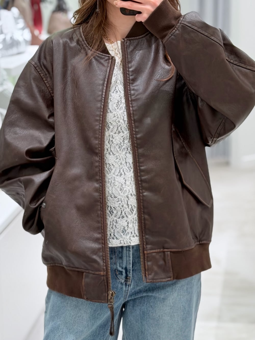 ブラウン系のライダースジャケット、ブルー系のデニムパンツを着用したレディースの春コーディネートの2枚目の写真