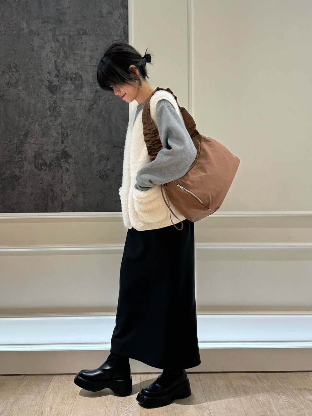 グレー系のスウェット、ブラック系のスカート、ブラック系のブーツを着用したレディースの冬コーディネートの2枚目の写真