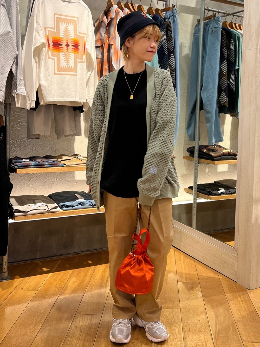 グリーン系のカーディガン/ボレロ、オレンジ系のショルダーバッグ、ベージュ系のその他パンツを着用したレディースの春コーディネートの2枚目の写真