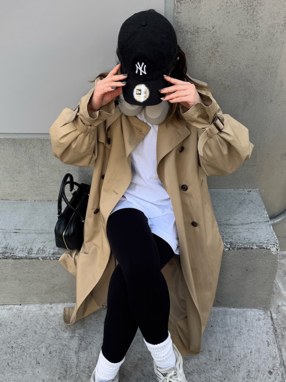 ベージュ系のトレンチコート、ブラック系のハンドバッグを着用したレディースの冬コーディネートの3枚目の写真