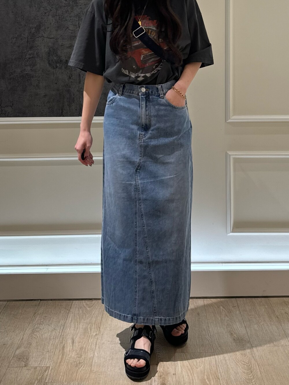 ブラック系のTシャツ/カットソー、ブルー系のデニムスカート、ブラック系のショルダーバッグを着用したレディースの春コーディネートの2枚目の写真