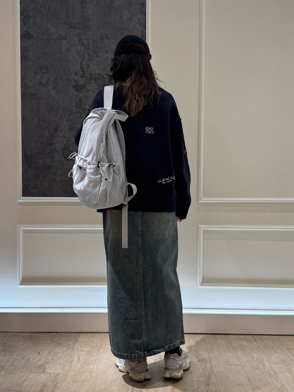 ホワイト系のカーディガン/ボレロ、ブルー系のデニムスカート、ブラック系のバックパック/リュックを着用したレディースの冬コーディネートの4枚目の写真