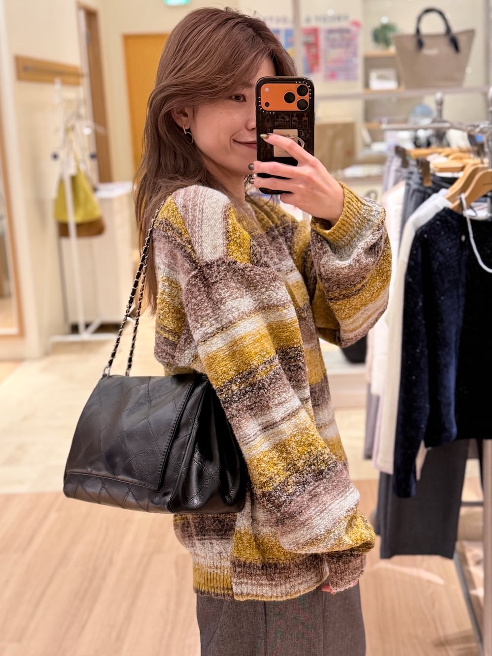 イエロー系のニット/セーター、グレー系のその他パンツ、ブラック系のショルダーバッグを着用したレディースの冬コーディネートの2枚目の写真