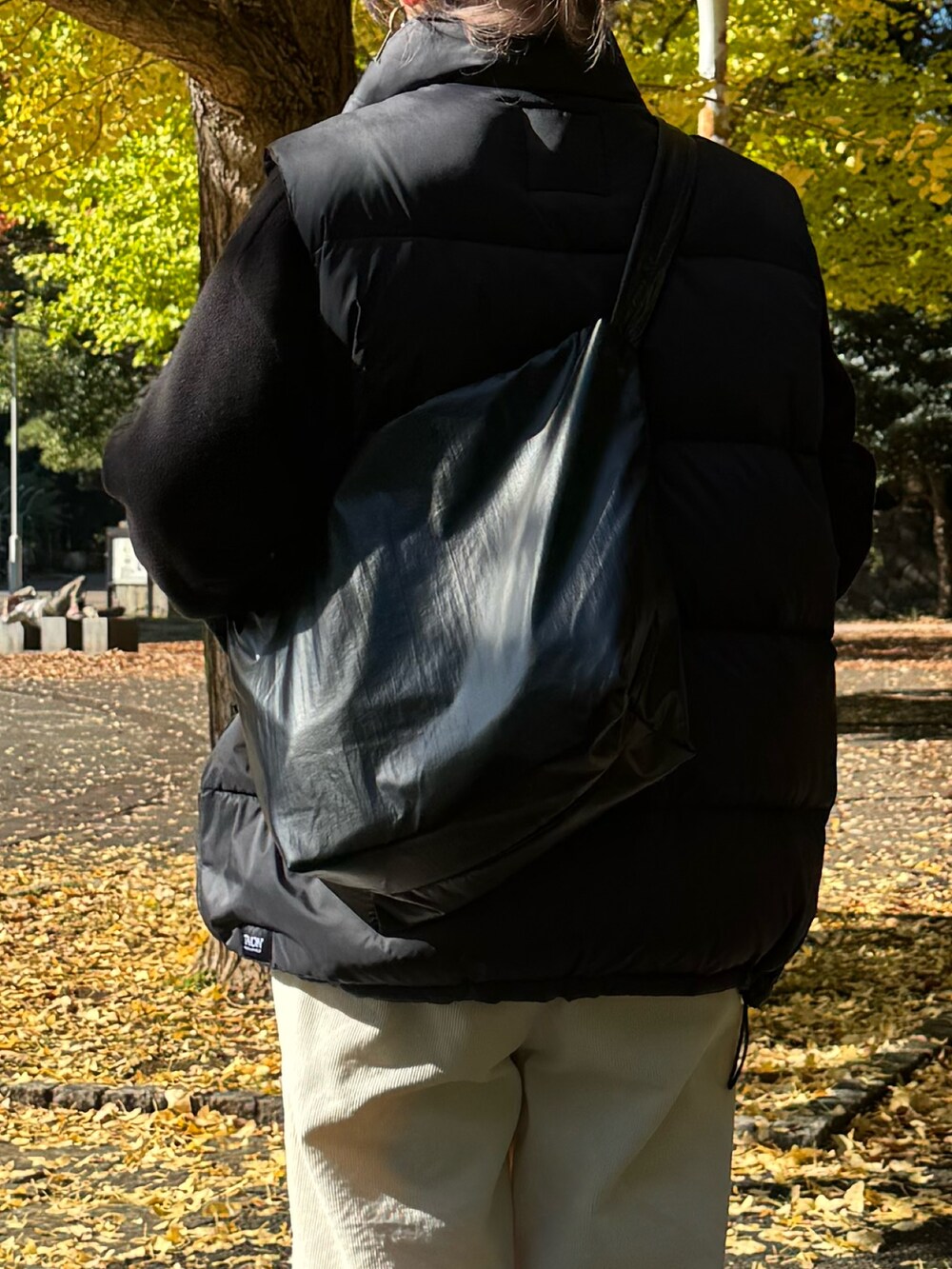 ブラック系のダウンベスト、ブラック系のニット/セーター、ホワイト系のその他パンツを着用したレディースの冬コーディネートの8枚目の写真