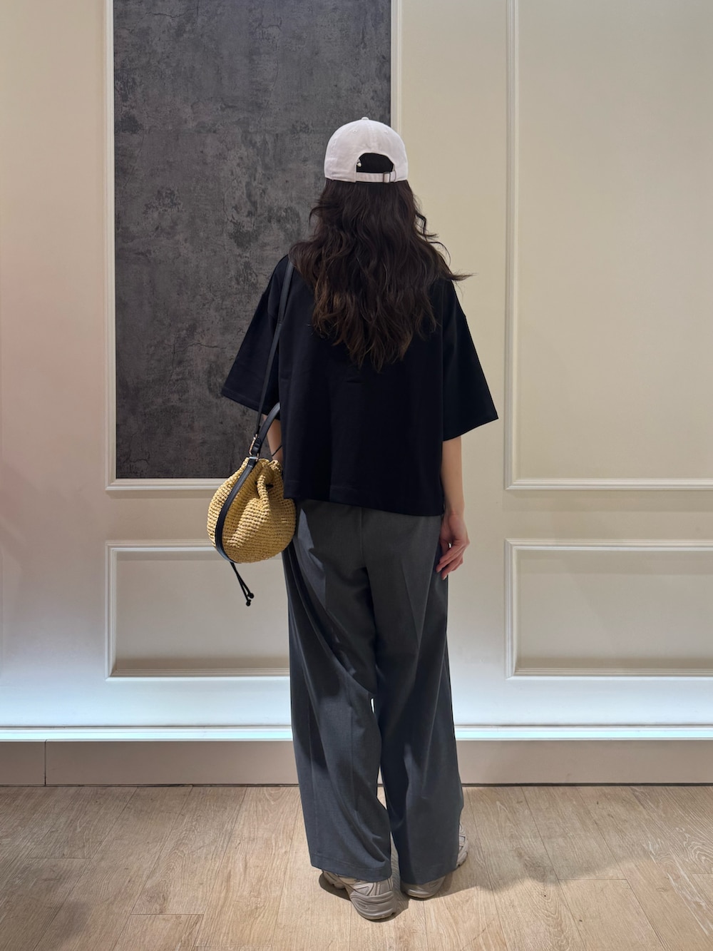 グレー系のTシャツ/カットソー、グレー系のスラックス、ベージュ系のかごバッグを着用したレディースの夏コーディネートの3枚目の写真