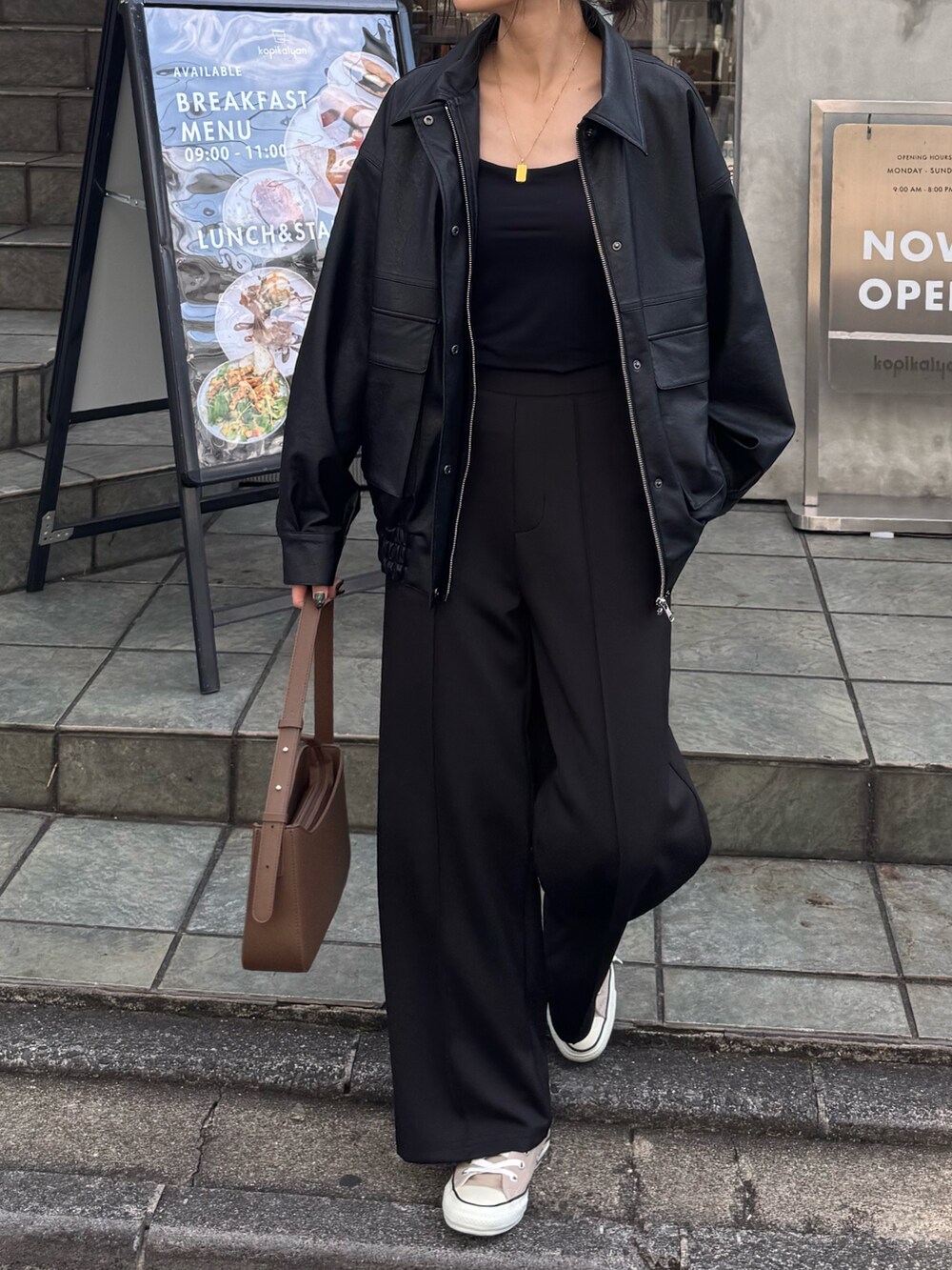 ブラウン系のブルゾン、ブラック系のその他パンツ、ホワイト系のハンドバッグを着用したレディースの秋コーディネートの4枚目の写真