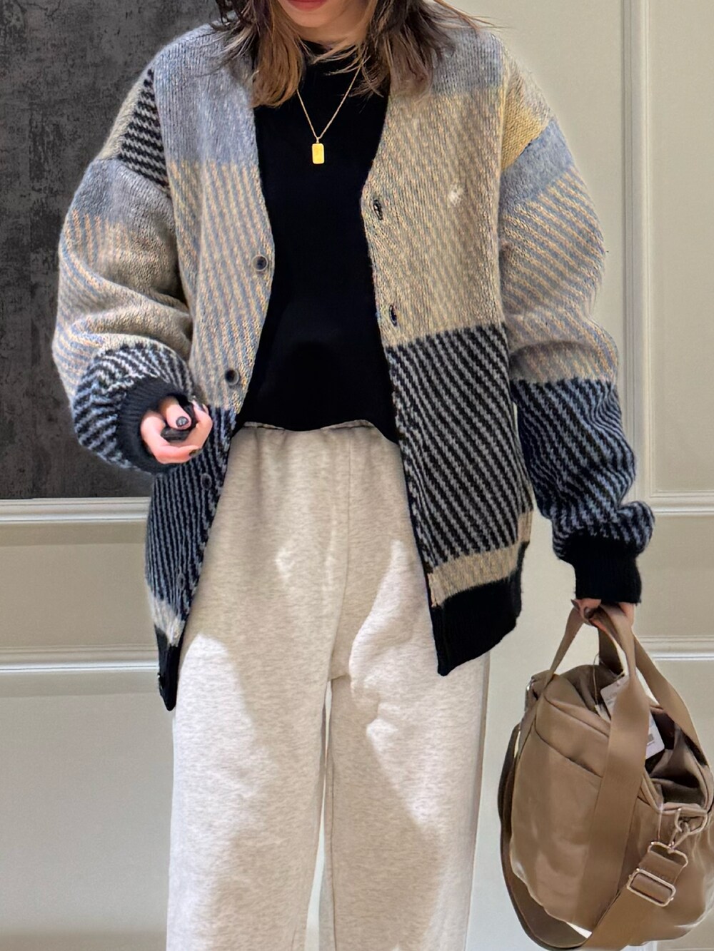 グレー系のカーディガン/ボレロ、グレー系のスウェットパンツ、ベージュ系のショルダーバッグを着用したレディースの秋コーディネートの3枚目の写真