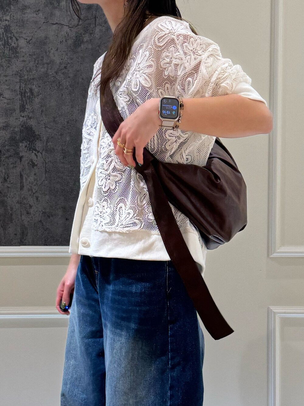 ブラック系のカーディガン/ボレロ、ブルー系のデニムパンツ、ブラウン系のショルダーバッグを着用したレディースの春コーディネートの2枚目の写真