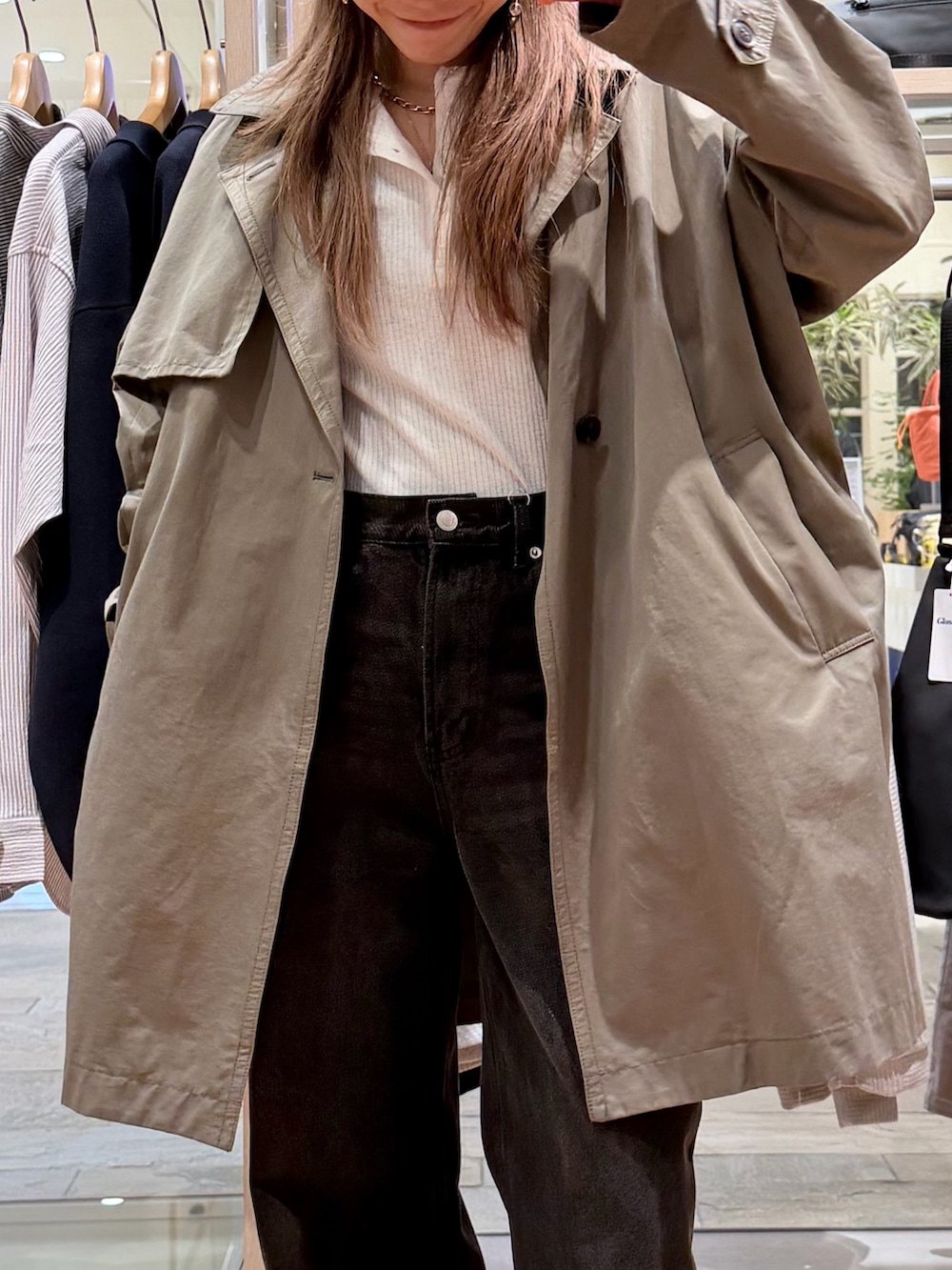 グリーン系のトレンチコート、ホワイト系のTシャツ/カットソー、ブルー系のデニムパンツを着用したレディースの春コーディネートの4枚目の写真