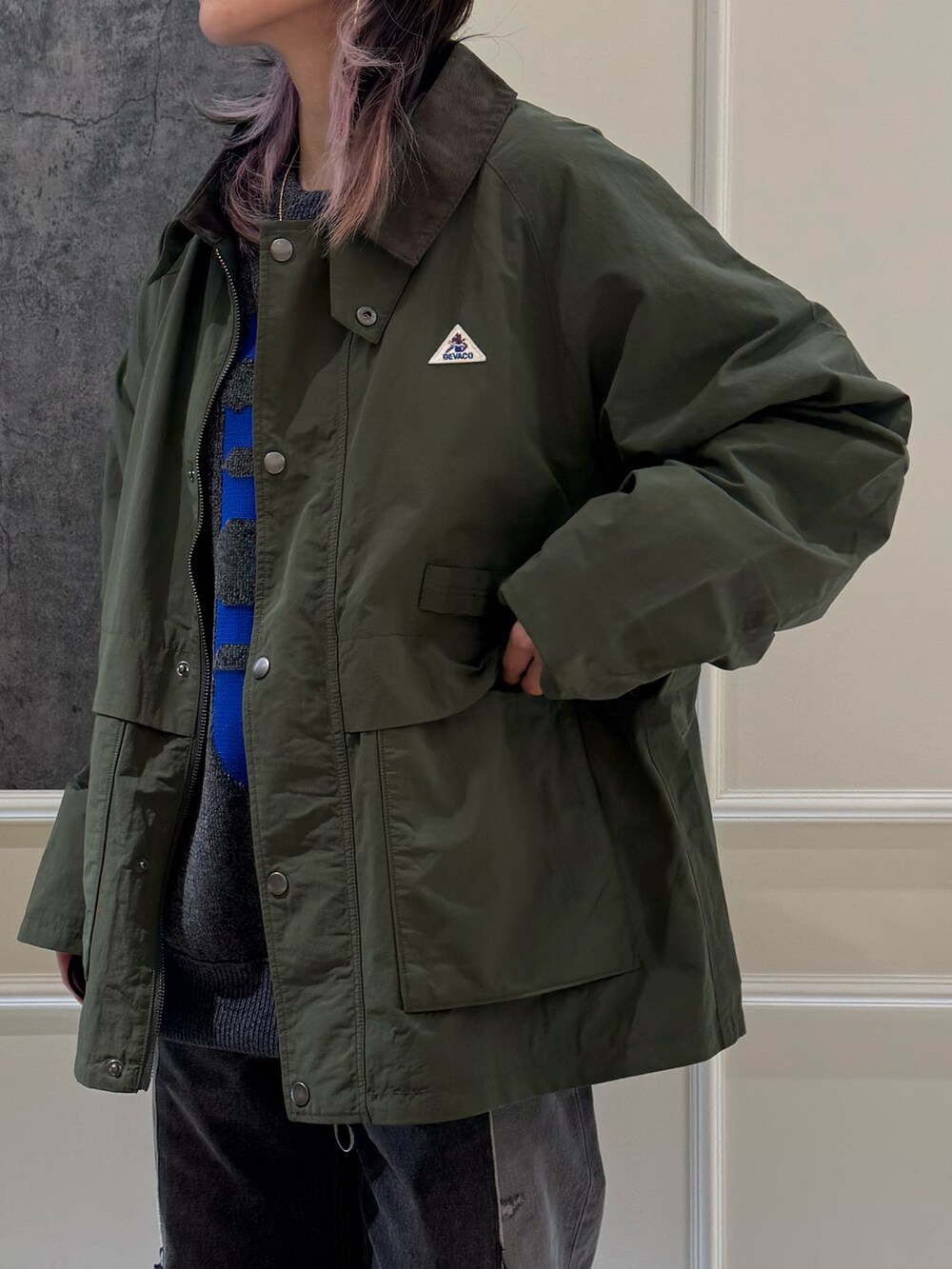 グリーン系のブルゾン、グレー系のニット/セーター、ブルー系のキャップを着用したレディースの秋コーディネートの3枚目の写真