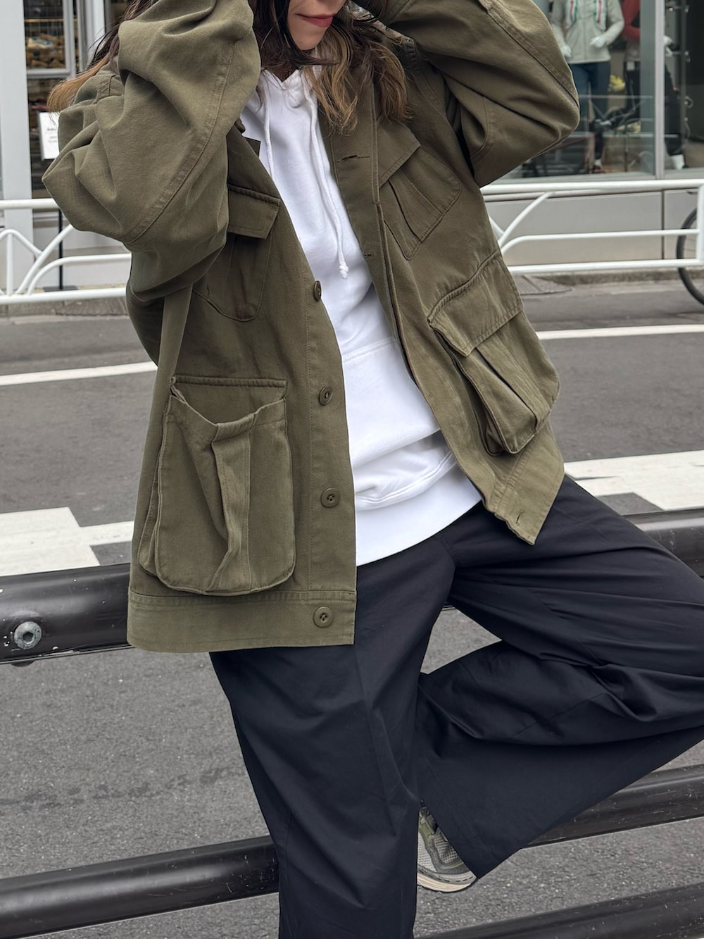 グリーン系のブルゾン、ホワイト系のパーカー、ベージュ系のチノパンツを着用したレディースの春コーディネートの2枚目の写真