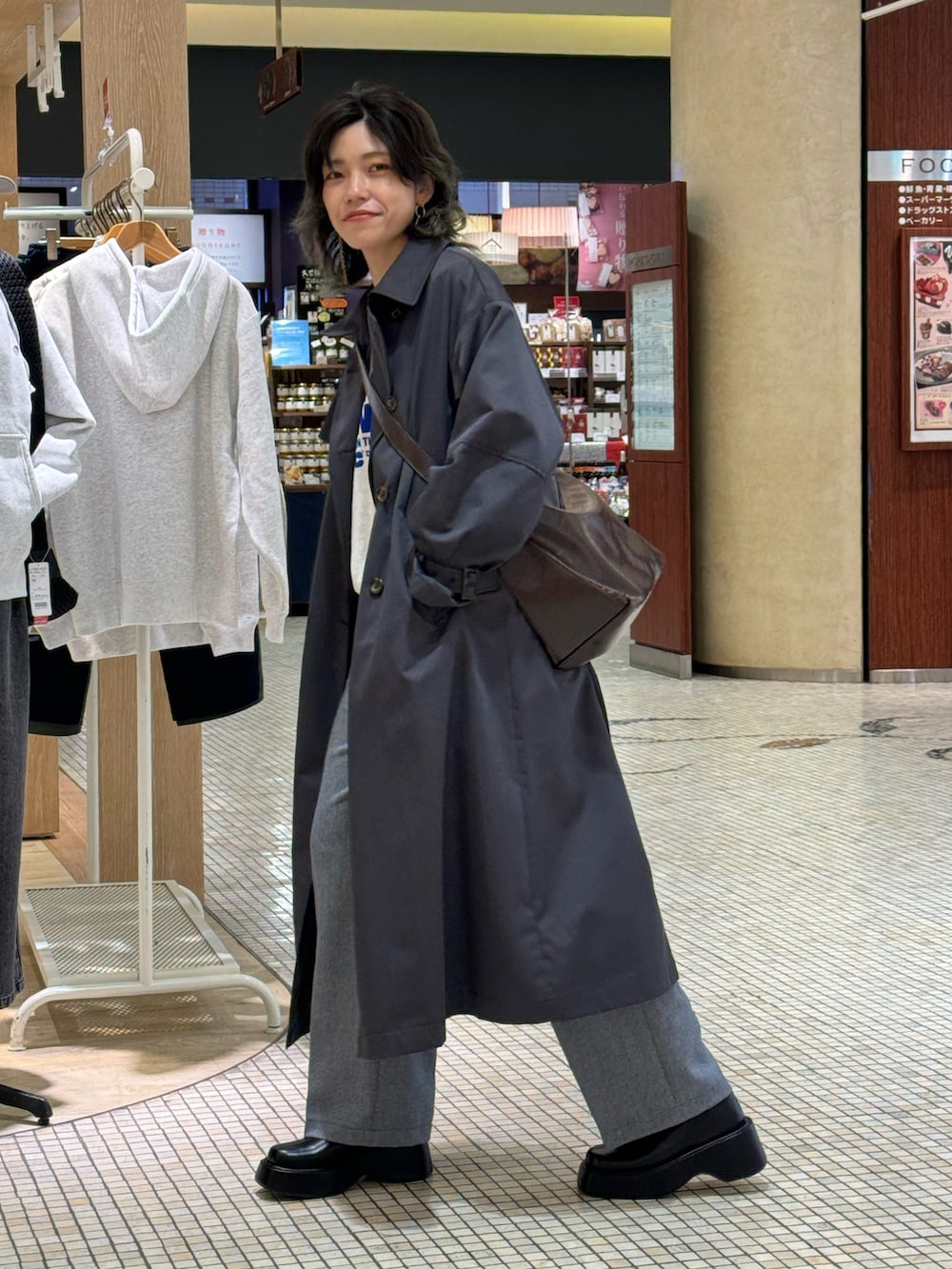 ブラウン系のショルダーバッグ、グレー系のトレンチコート、グレー系のスウェットを着用したレディースの冬コーディネートの2枚目の写真