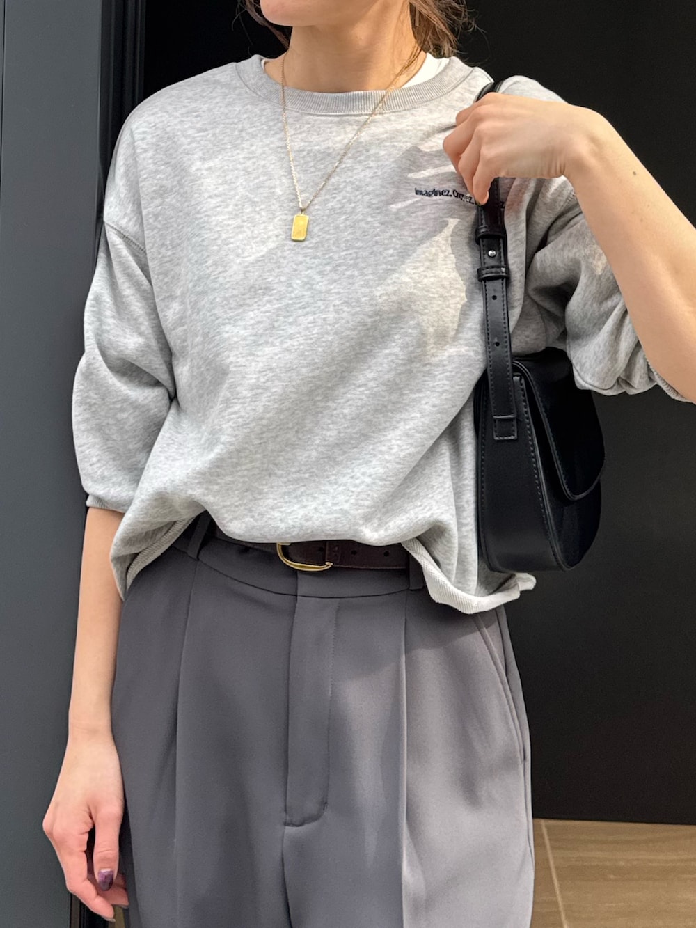 グレー系のスウェット、グレー系のスラックス、ブラック系のショルダーバッグを着用したレディースの春コーディネートの2枚目の写真