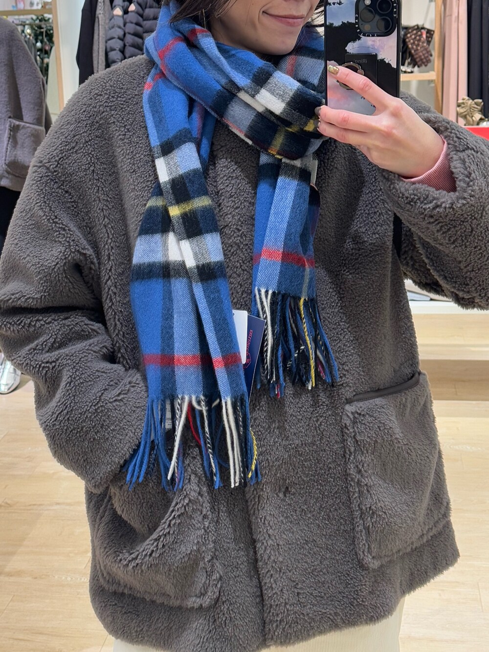 ブラウン系のノーカラーコート、ホワイト系のその他パンツ、ブルー系のストール/ショールを着用したレディースの冬コーディネートの2枚目の写真