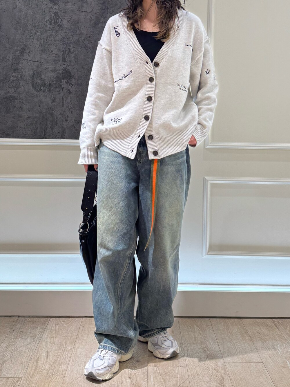 ホワイト系のカーディガン/ボレロ、ブルー系のデニムパンツ、ブラック系のショルダーバッグを着用したレディースの冬コーディネートの2枚目の写真