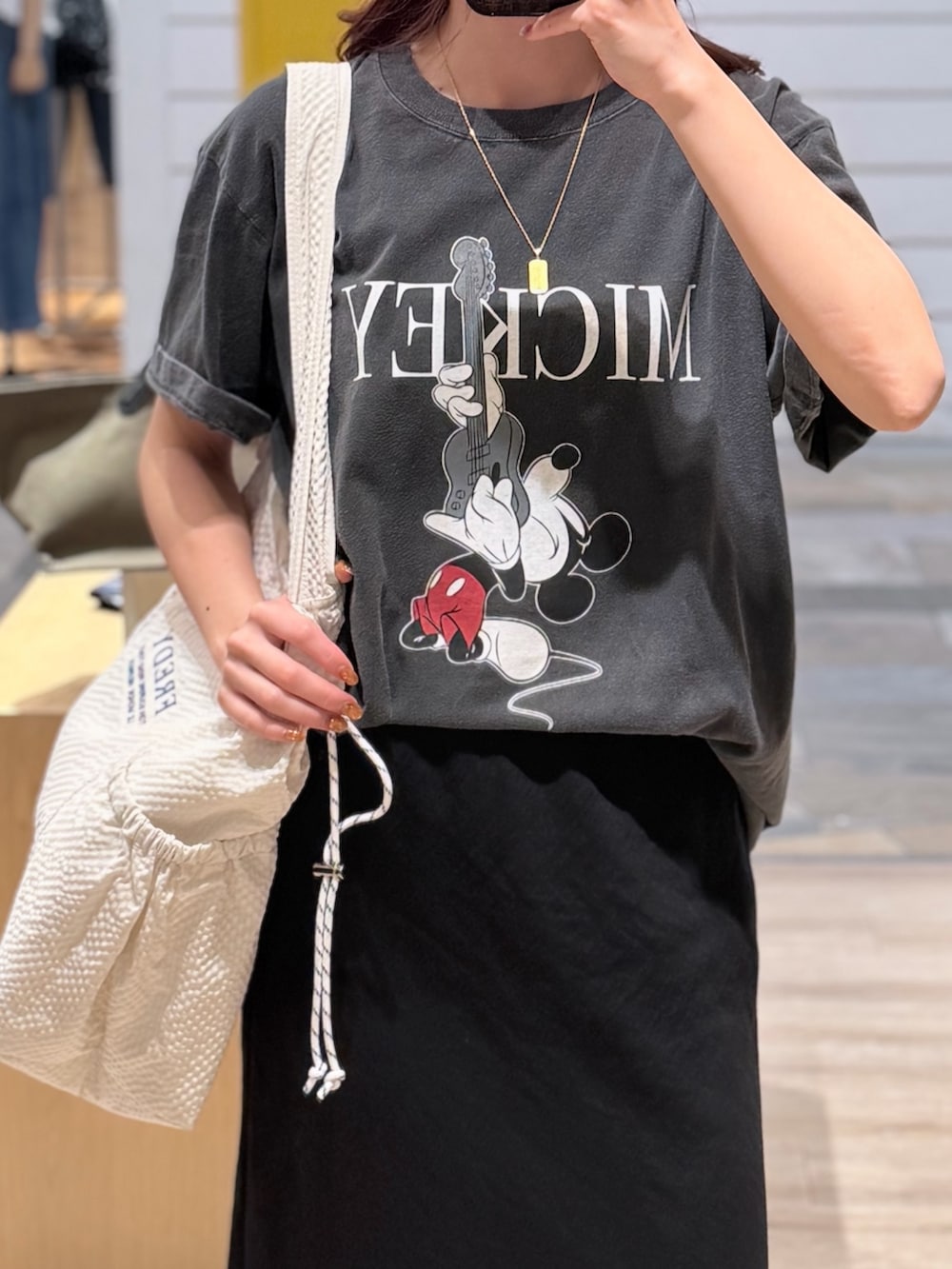 グレー系のTシャツ/カットソー、ブラック系のスカート、ホワイト系のトートバッグを着用したレディースの夏コーディネートの2枚目の写真