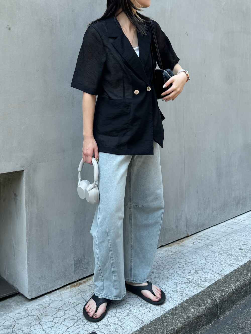 ブラック系のダウンジャケット/コート、ブルー系のデニムパンツ、ホワイト系のボストンバッグを着用したレディースの夏コーディネートの2枚目の写真