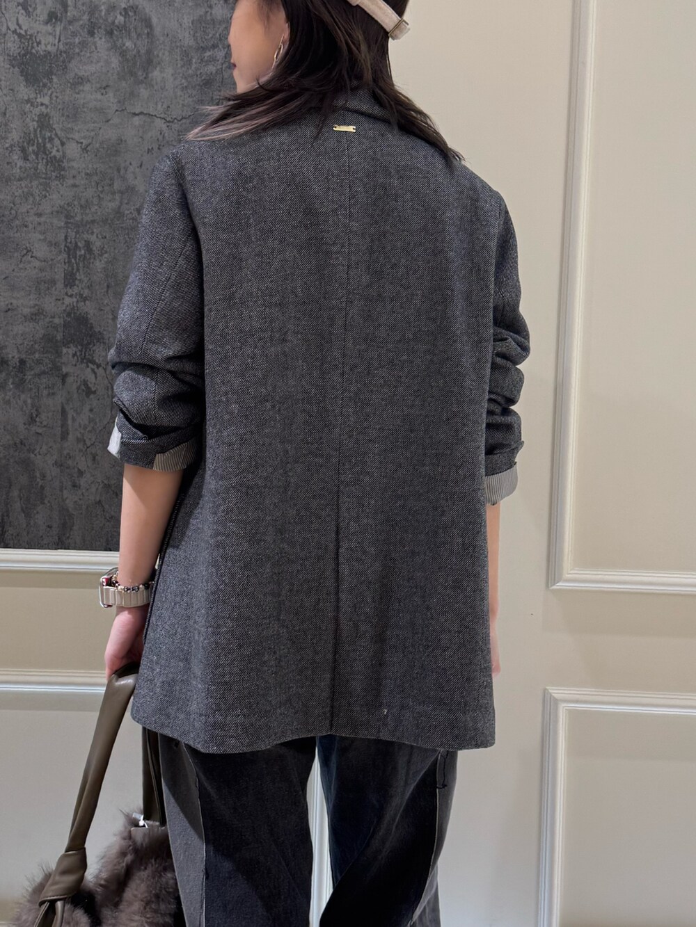 グレー系のテーラードジャケット、ベージュ系のハンドバッグ、ブルー系のキャップを着用したレディースの秋コーディネートの2枚目の写真