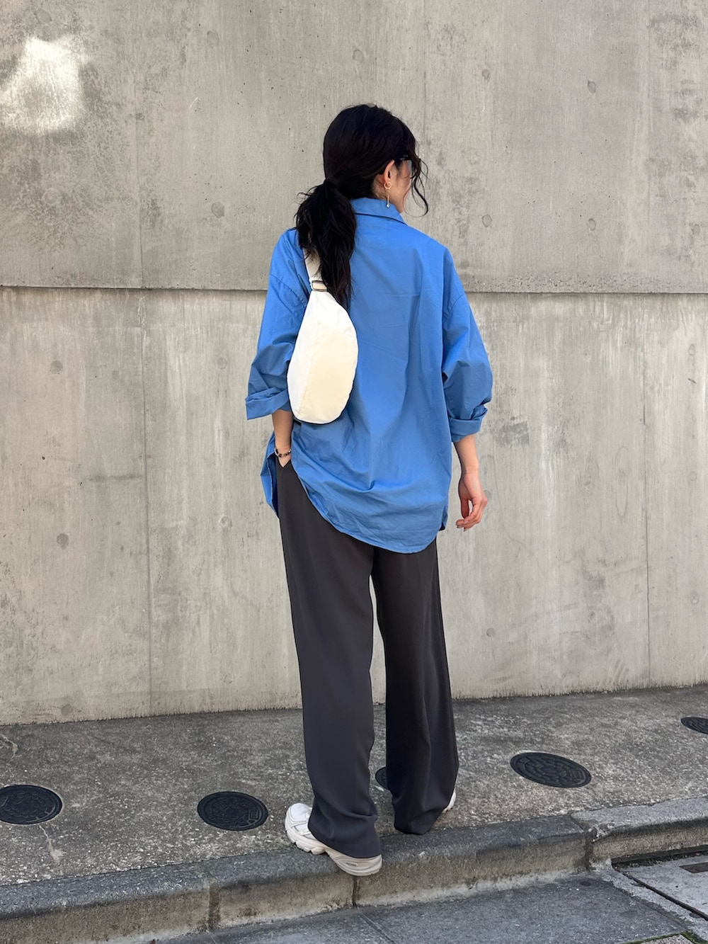 ブルー系のシャツ/ブラウス、グレー系のスラックス、ホワイト系のショルダーバッグを着用したレディースの春コーディネートの5枚目の写真