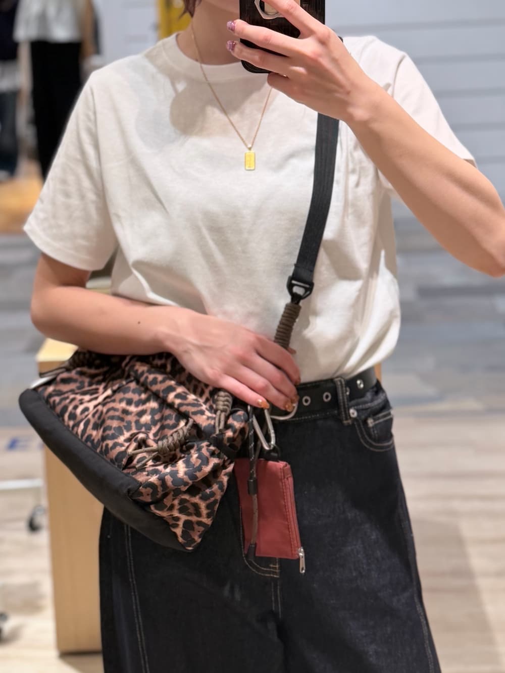 ブラウン系のショルダーバッグ、ホワイト系のTシャツ/カットソー、ブルー系のデニムパンツを着用したレディースの夏コーディネートの3枚目の写真