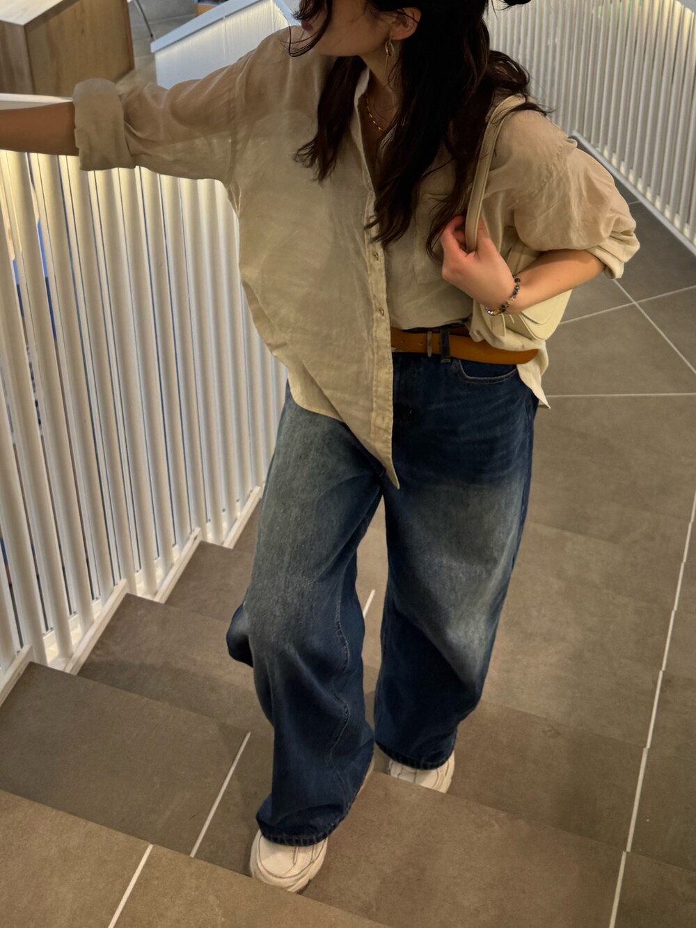 ベージュ系のシャツ/ブラウス、ブルー系のデニムパンツを着用したレディースの春コーディネートの2枚目の写真