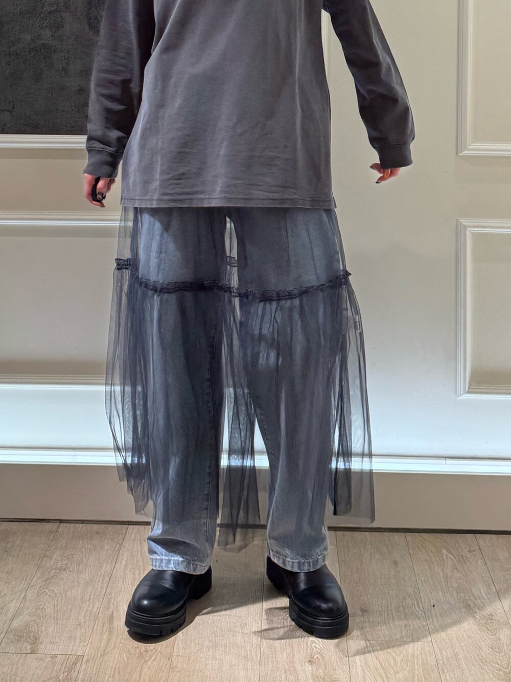 グレー系のTシャツ/カットソー、グレー系のスカート、ブルー系のデニムパンツを着用したレディースの冬コーディネートの2枚目の写真