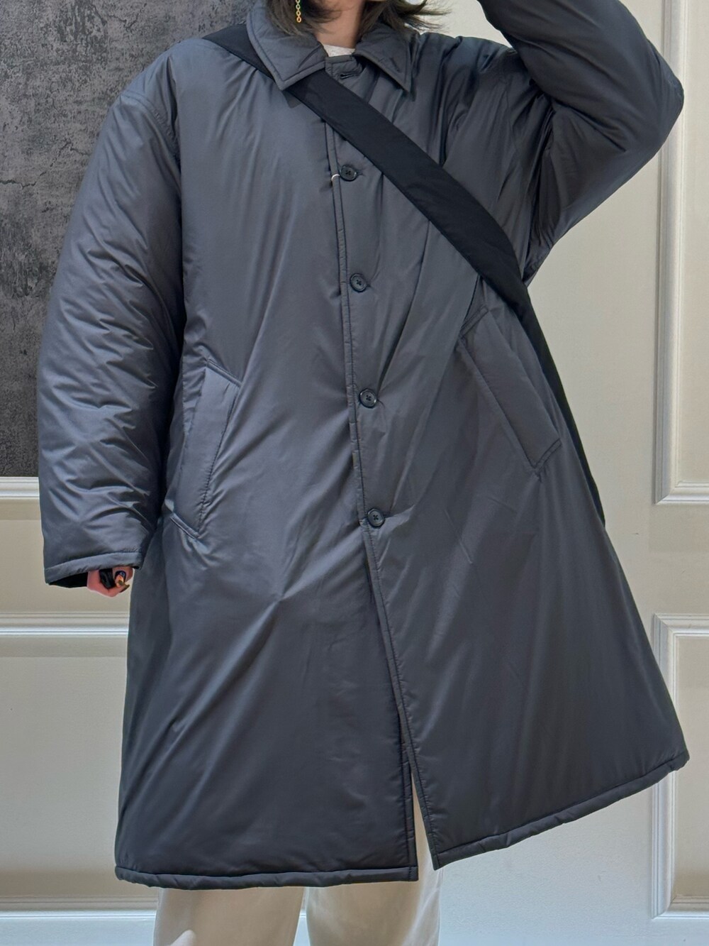 グレー系のステンカラーコート、ホワイト系のカーゴパンツ、グリーン系のキャップを着用したレディースの冬コーディネートの2枚目の写真