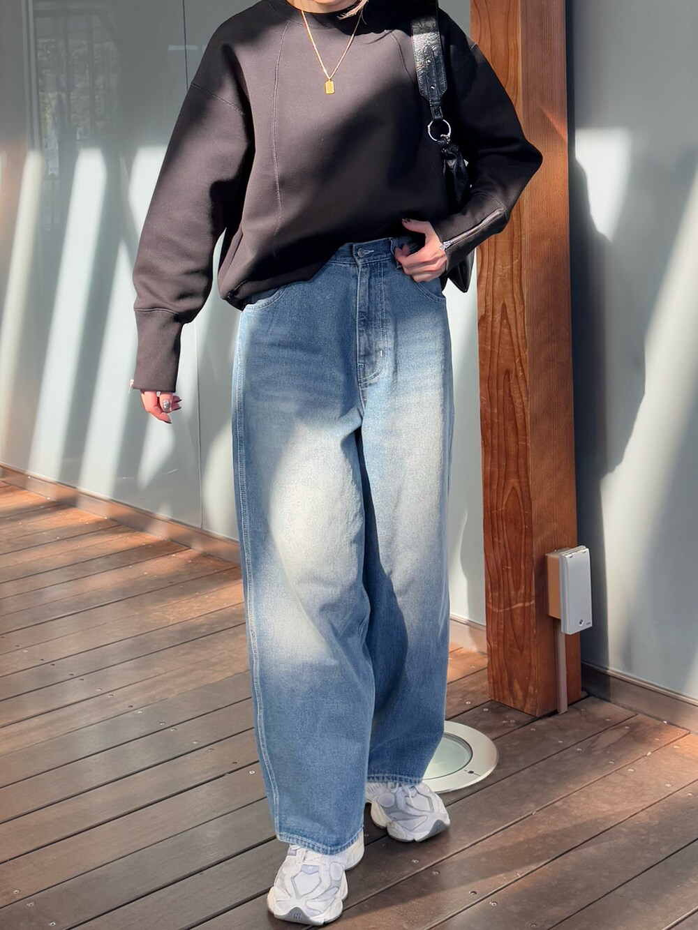 ブラック系のスウェット、ブルー系のデニムパンツ、ホワイト系のショルダーバッグを着用したレディースの冬コーディネートの4枚目の写真