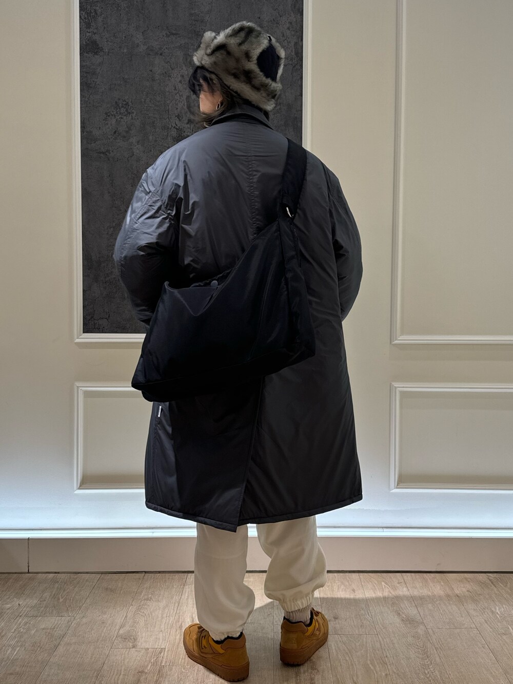 グレー系のステンカラーコート、ホワイト系のカーゴパンツ、グリーン系のキャップを着用したレディースの冬コーディネートの3枚目の写真