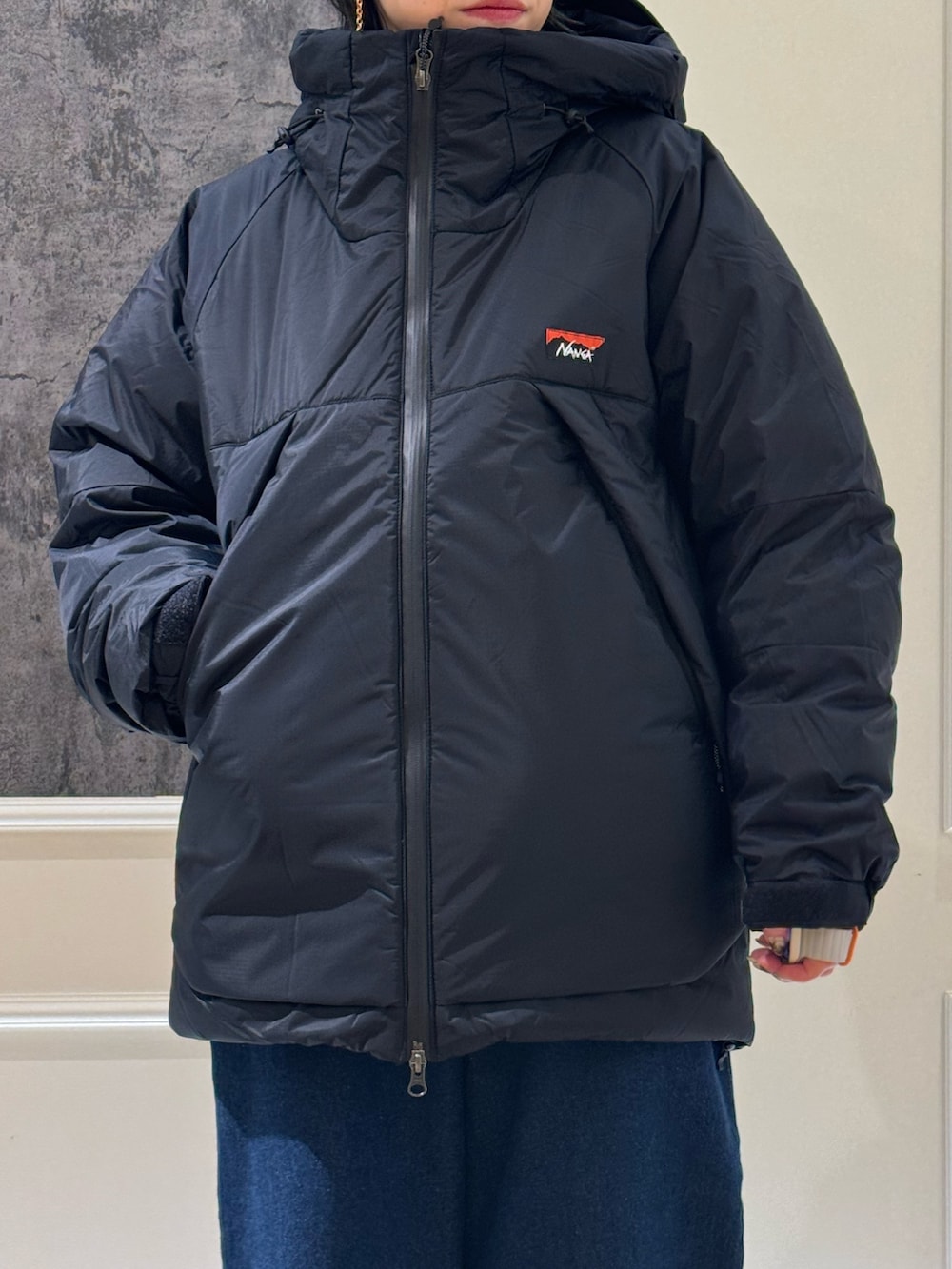 ブラック系のスウェット、ブラック系のダウンジャケット/コート、ブルー系のデニムパンツを着用したレディースの冬コーディネートの3枚目の写真