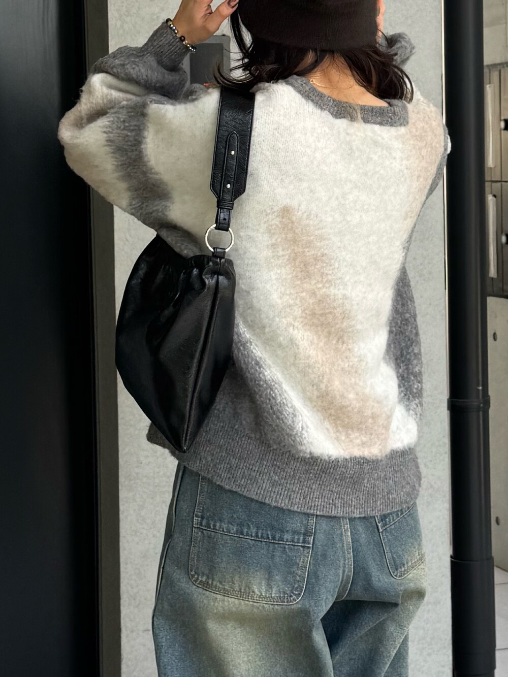 グレー系のニット/セーター、ブルー系のデニムパンツ、ブラック系のショルダーバッグを着用したレディースの冬コーディネートの6枚目の写真