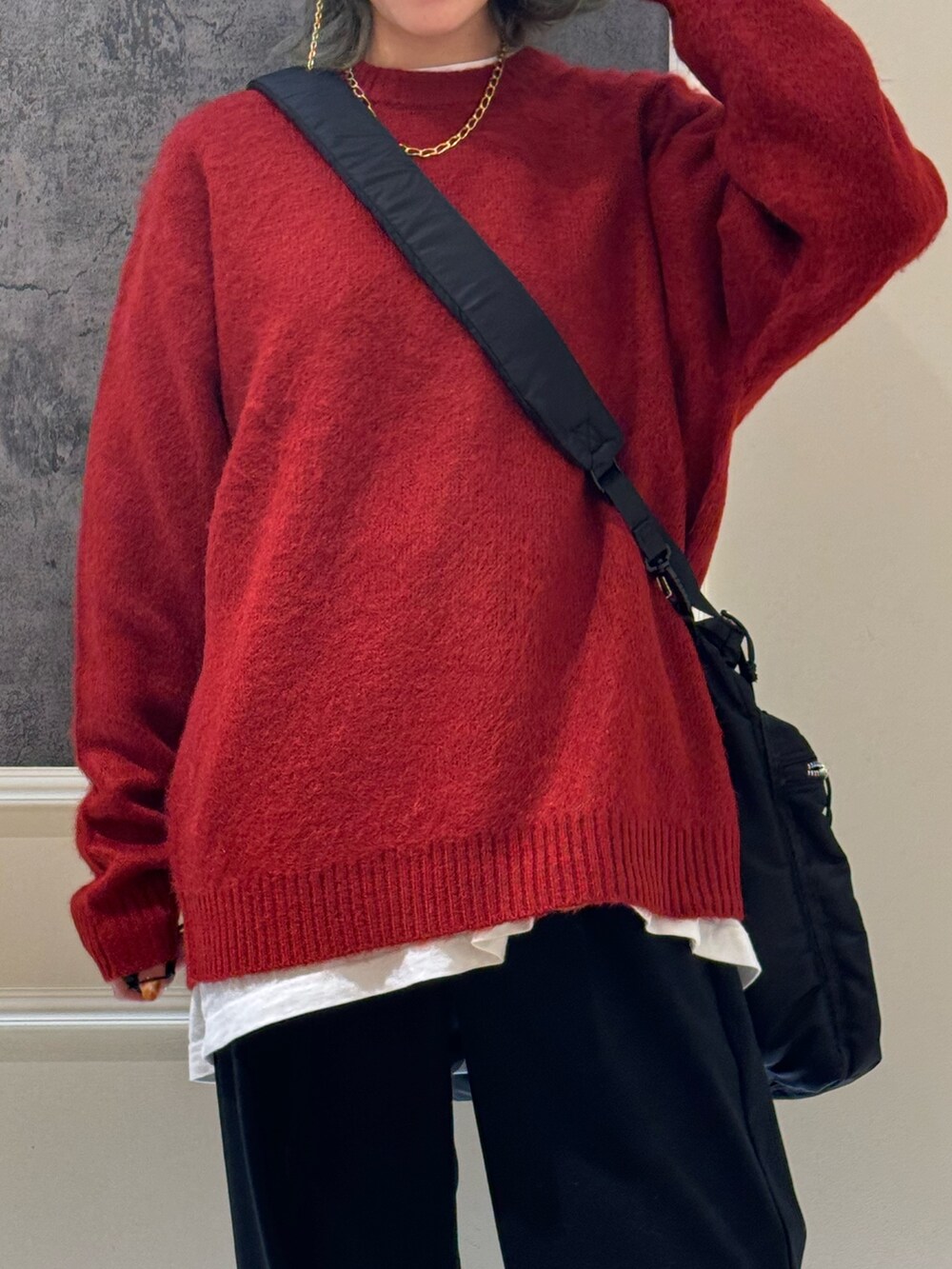 レッド系のニット/セーター、ブラック系のショルダーバッグ、ブラック系のスラックスを着用したレディースの冬コーディネートの3枚目の写真