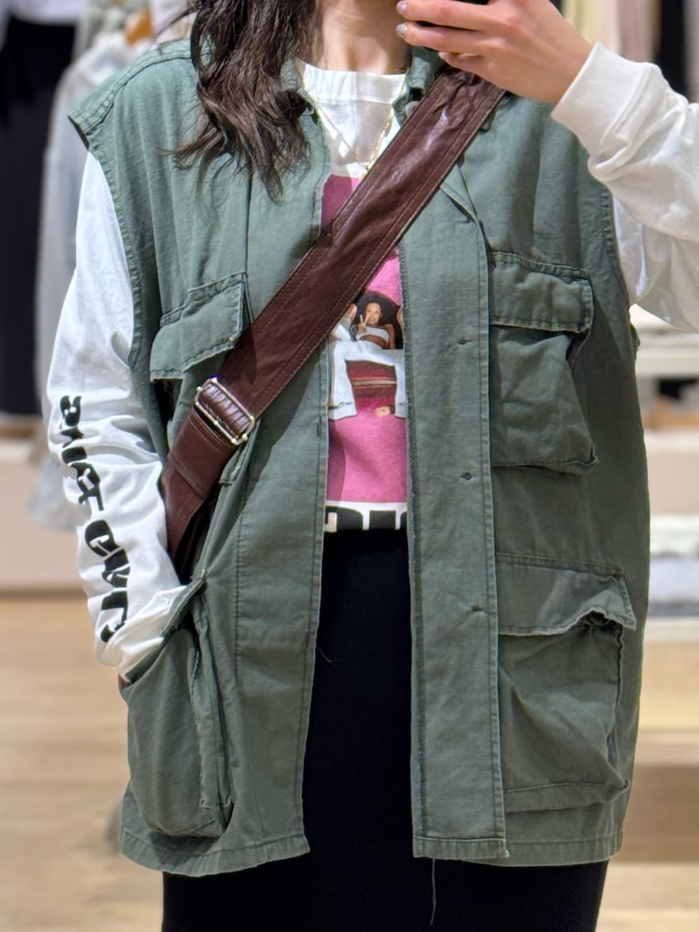 グリーン系のミリタリージャケット、ホワイト系のTシャツ/カットソー、ブラウン系のショルダーバッグを着用したレディースの春コーディネートの2枚目の写真