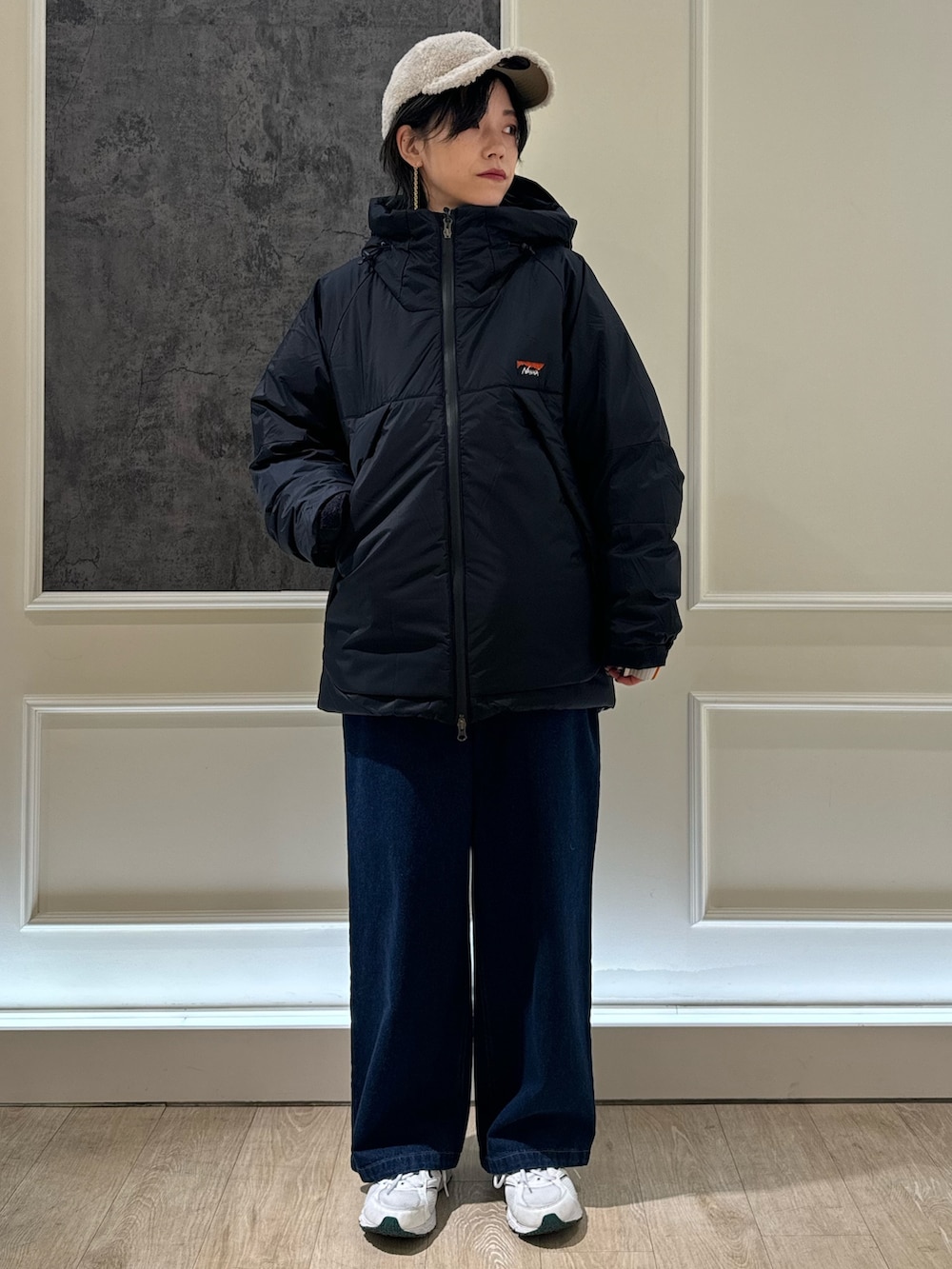 ブラック系のスウェット、ブラック系のダウンジャケット/コート、ブルー系のデニムパンツを着用したレディースの冬コーディネートの2枚目の写真