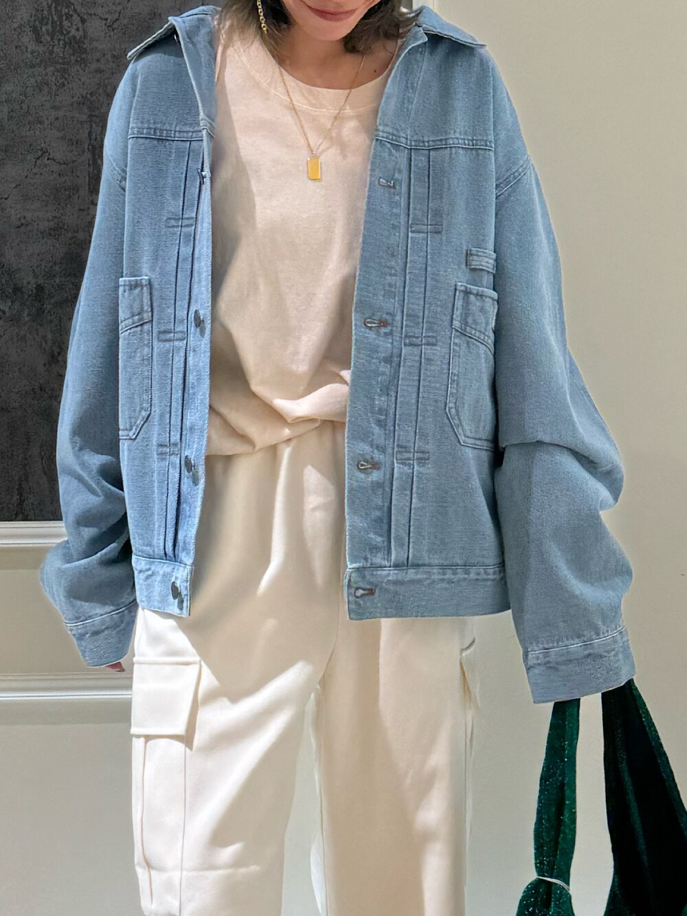 ブルー系のデニムジャケット、オレンジ系のトートバッグ、ホワイト系のカーゴパンツを着用したレディースの冬コーディネートの2枚目の写真