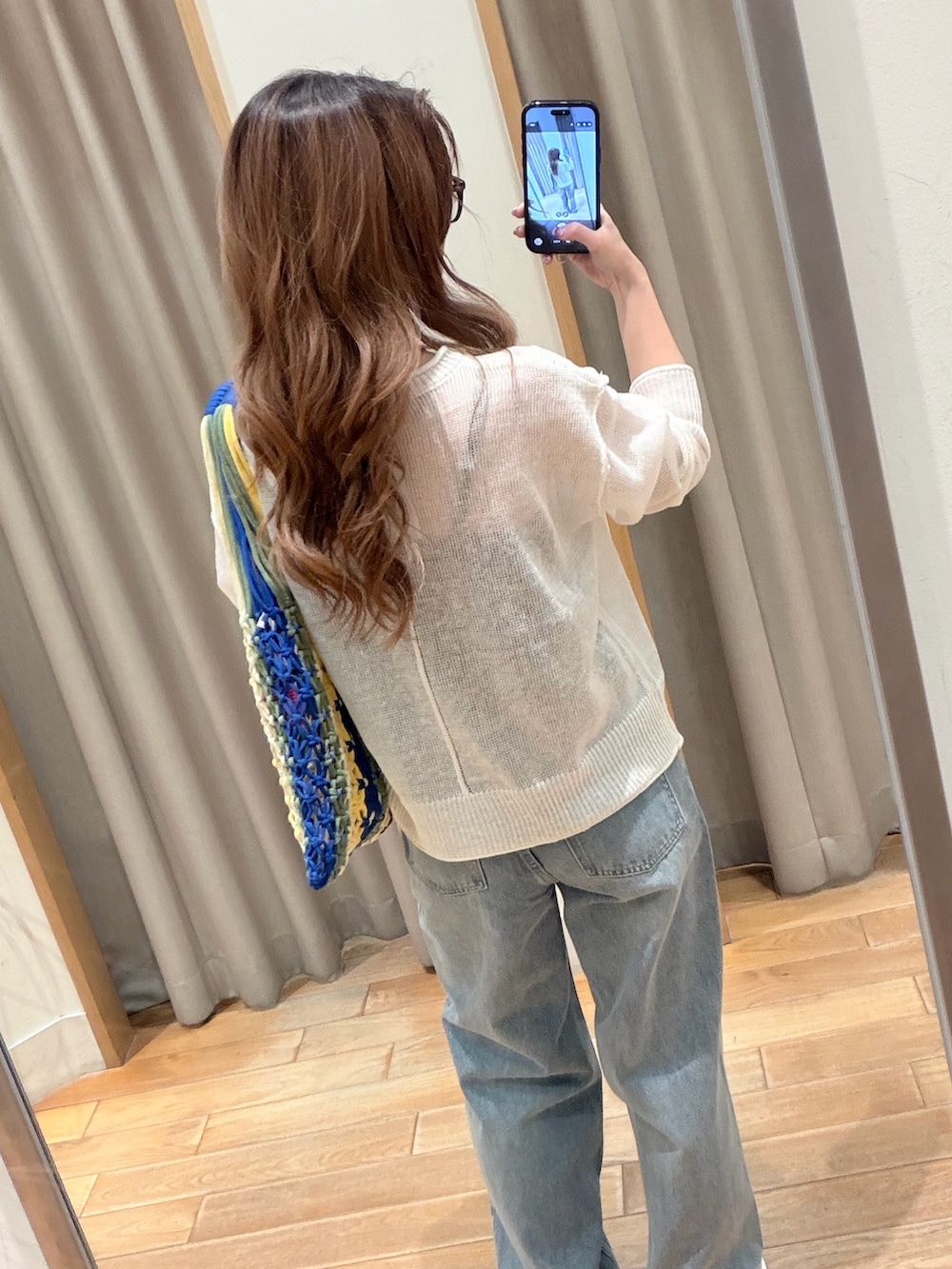 ホワイト系のニット/セーター、ブルー系のデニムパンツ、ブラック系のトートバッグを着用したレディースの春コーディネートの4枚目の写真