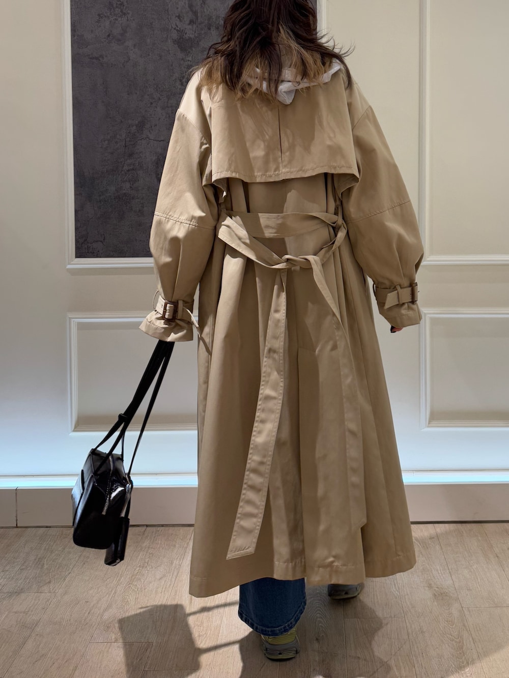 グレー系のニット/セーター、ベージュ系のトレンチコート、ブルー系のデニムパンツを着用したレディースの冬コーディネートの3枚目の写真