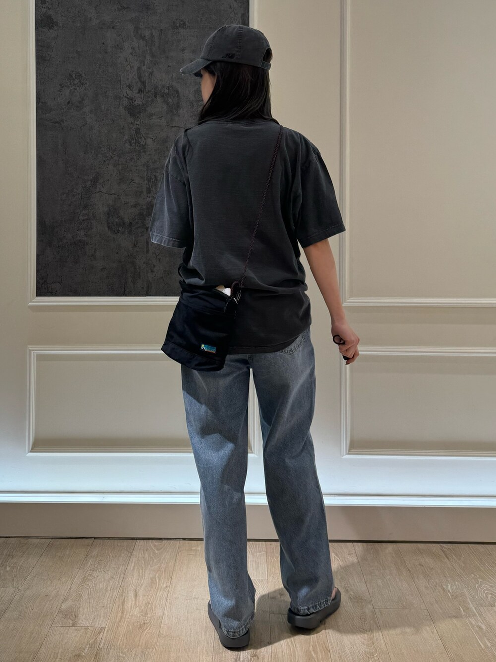 ブラック系のTシャツ/カットソー、ブラック系のデニムパンツ、グレー系のサンダルを着用したレディースの春コーディネートの3枚目の写真