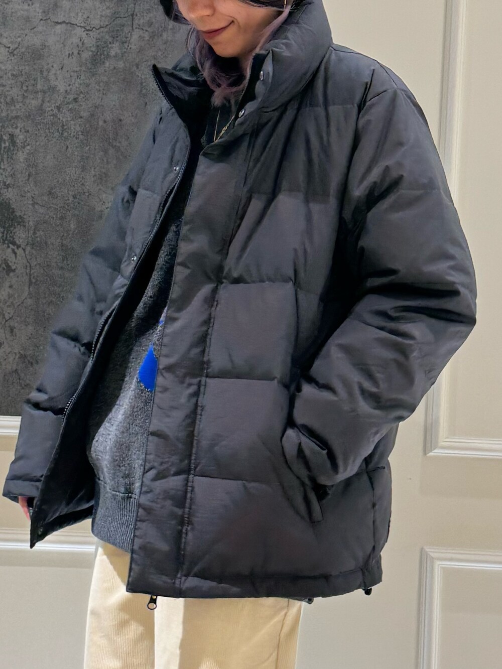 グレー系のダウンジャケット/コート、グレー系のニット/セーター、ブルー系のキャップを着用したレディースの秋コーディネートの3枚目の写真