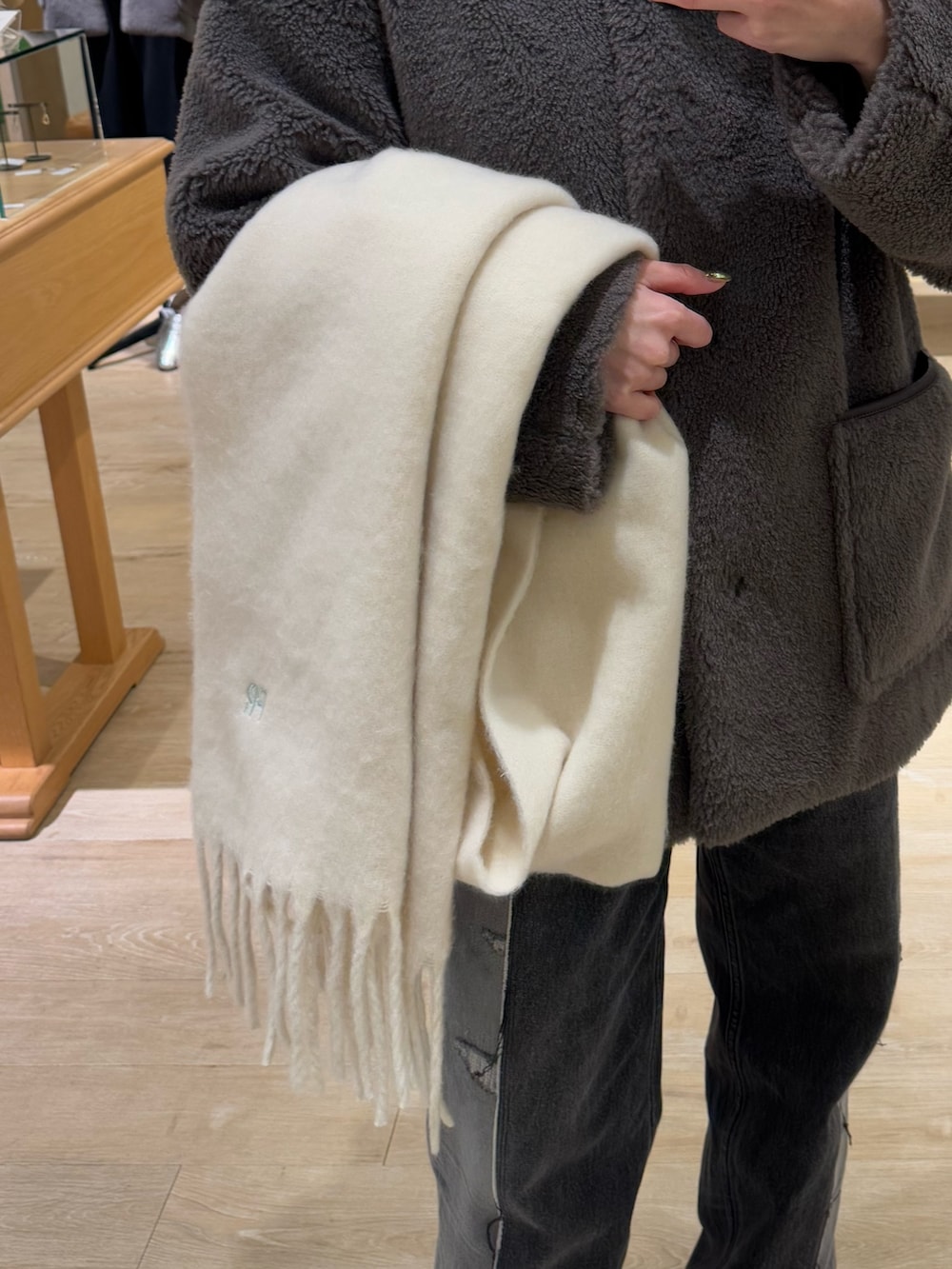 ブラウン系のノーカラーコート、ホワイト系のストール/ショールを着用したレディースの冬コーディネートの3枚目の写真