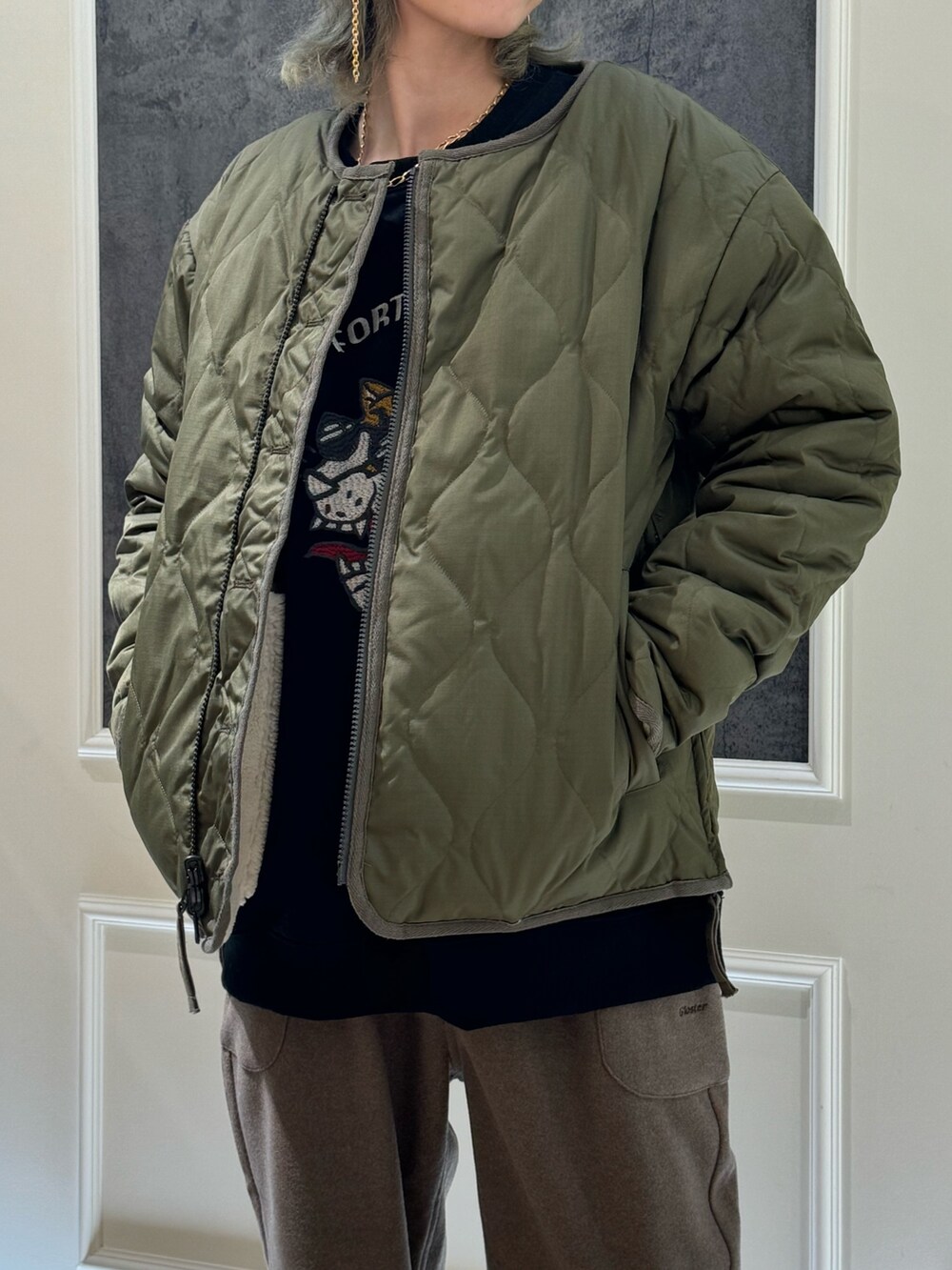 グリーン系のダウンジャケット/コート、ブラック系のスウェット、ブラウン系のその他パンツを着用したレディースの秋コーディネートの2枚目の写真