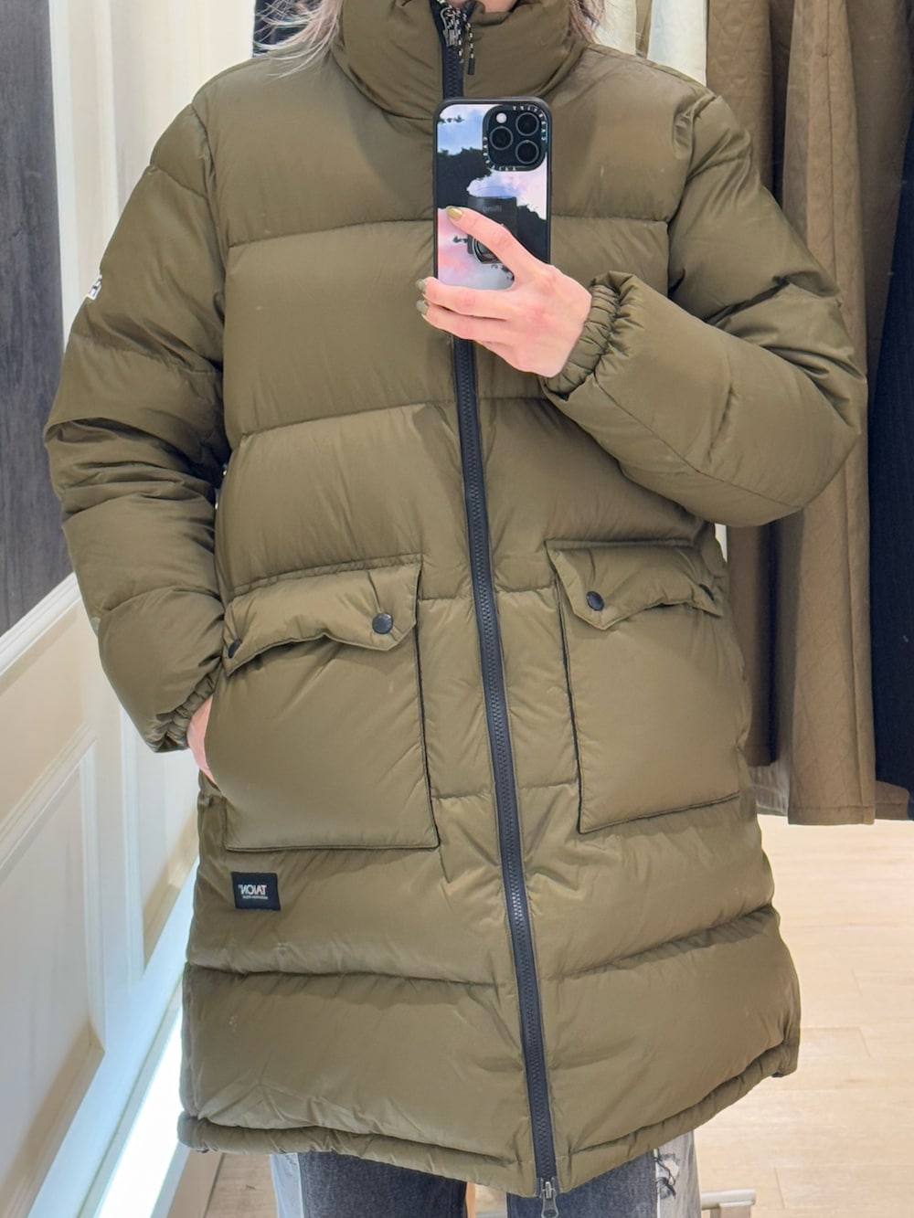 グリーン系のダウンジャケット/コート、ブルー系のキャップを着用したレディースの冬コーディネートの2枚目の写真