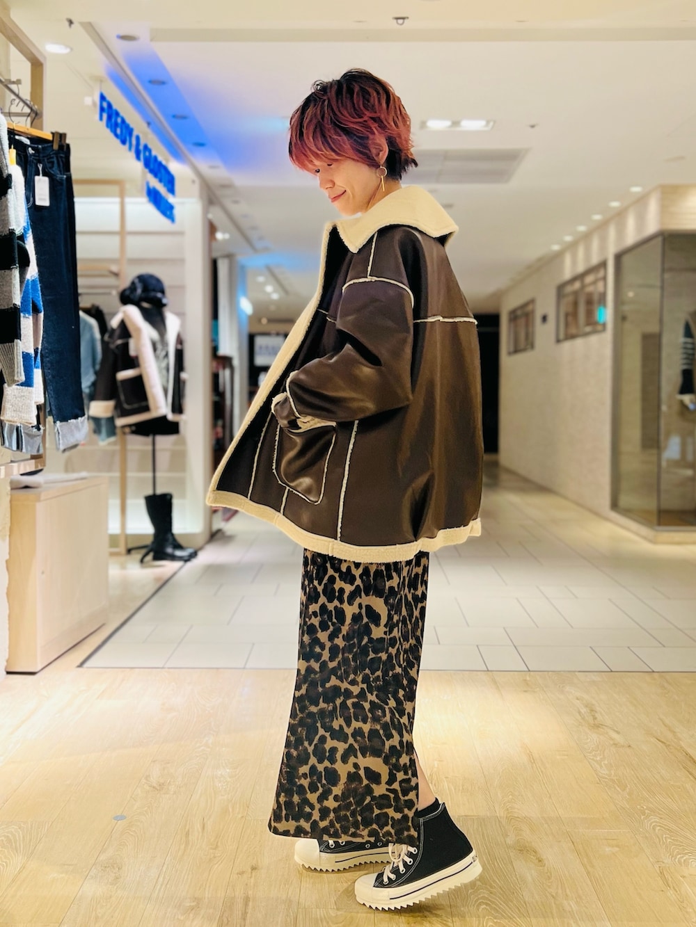 ベージュ系のスカート、ホワイト系のスウェット、ブラウン系のムートンコートを着用したレディースの冬コーディネートの2枚目の写真