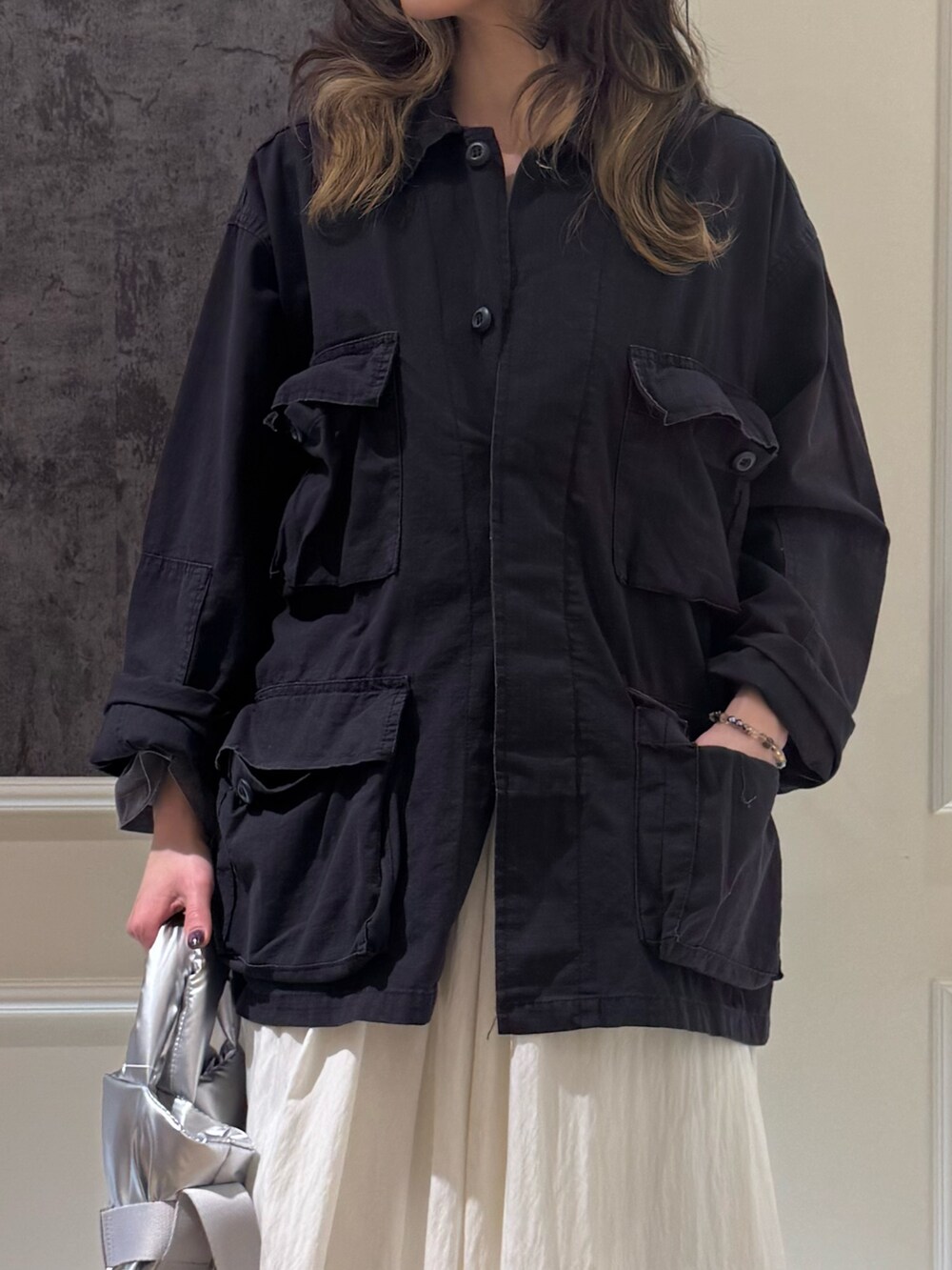 ブラック系のミリタリージャケット、ホワイト系のスカート、シルバー系のショルダーバッグを着用したレディースの春コーディネートの2枚目の写真